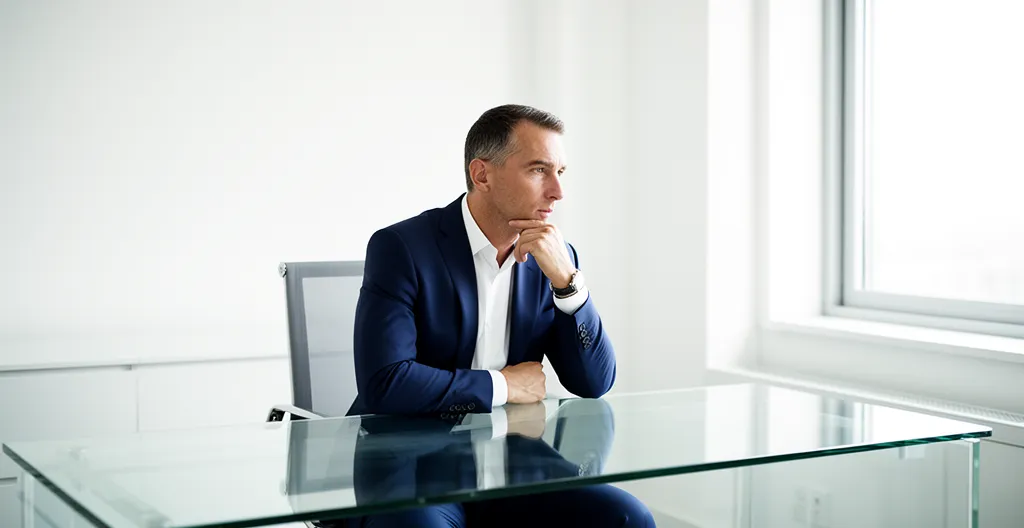 Entrepreneur en réflexion dans un bureau moderne avec documents financiers et calculatrice